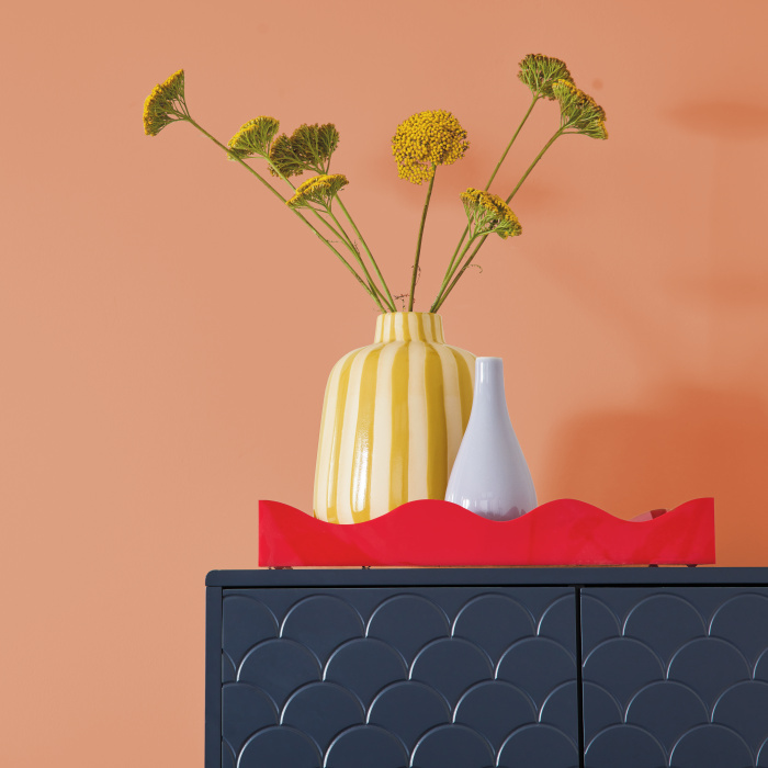 Colorful vase styled in front of a coral wall